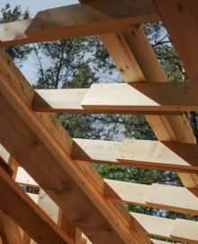 Close-up view of wooden beams forming a house roof structure against a sky background.