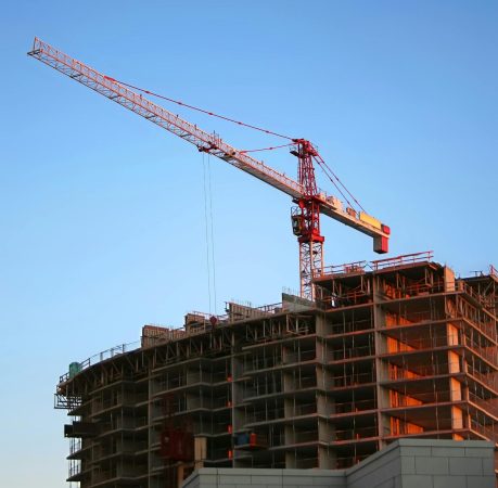 Tower crane on a high-rise building under construction at sunset, showcasing modern urban development.
